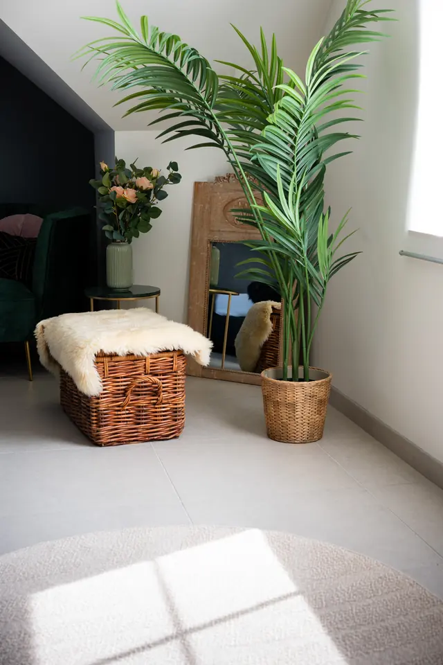 Hoek van de daglichtstudio met raam, plant en rieten mand